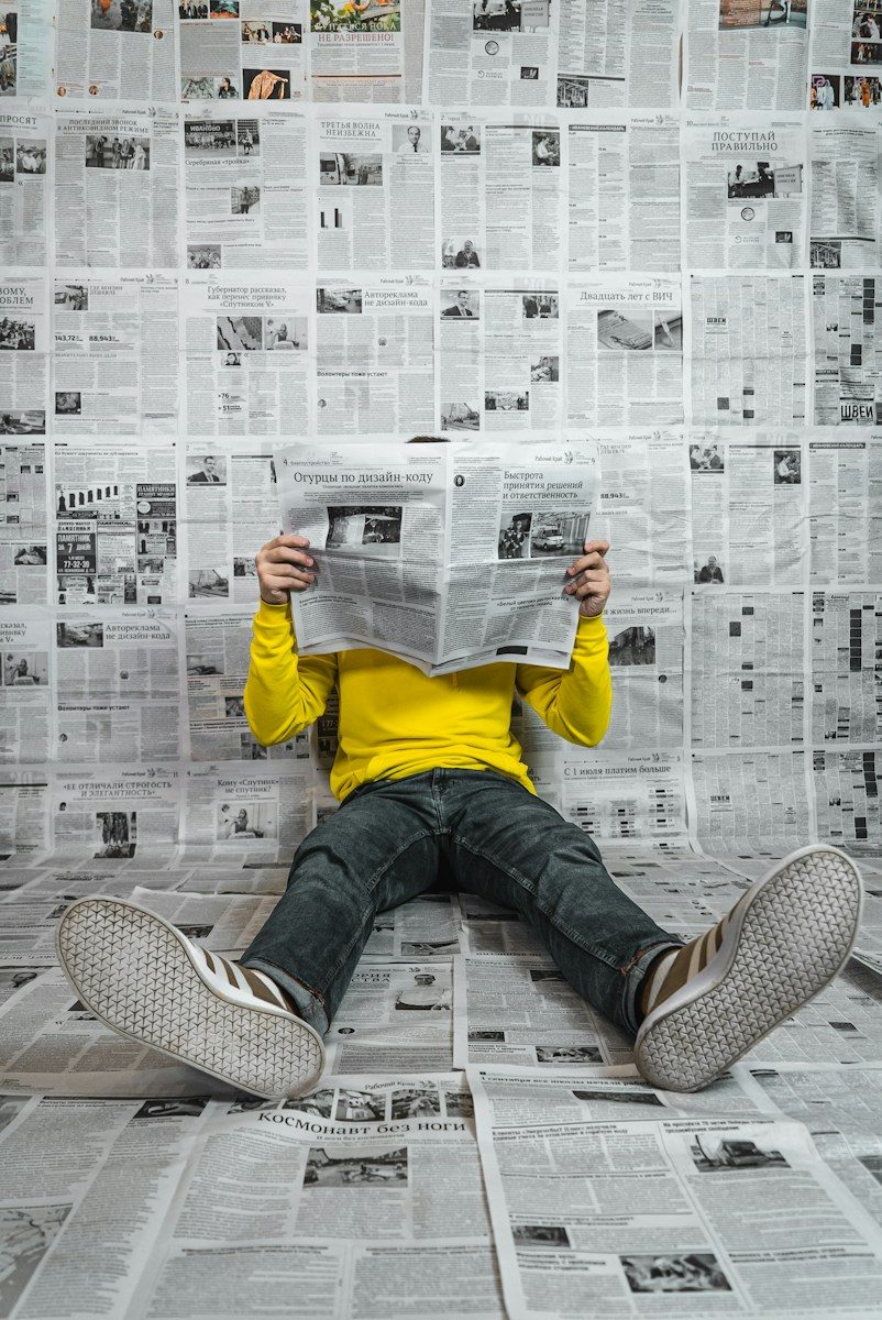 a person sitting on the floor reading a newspaper